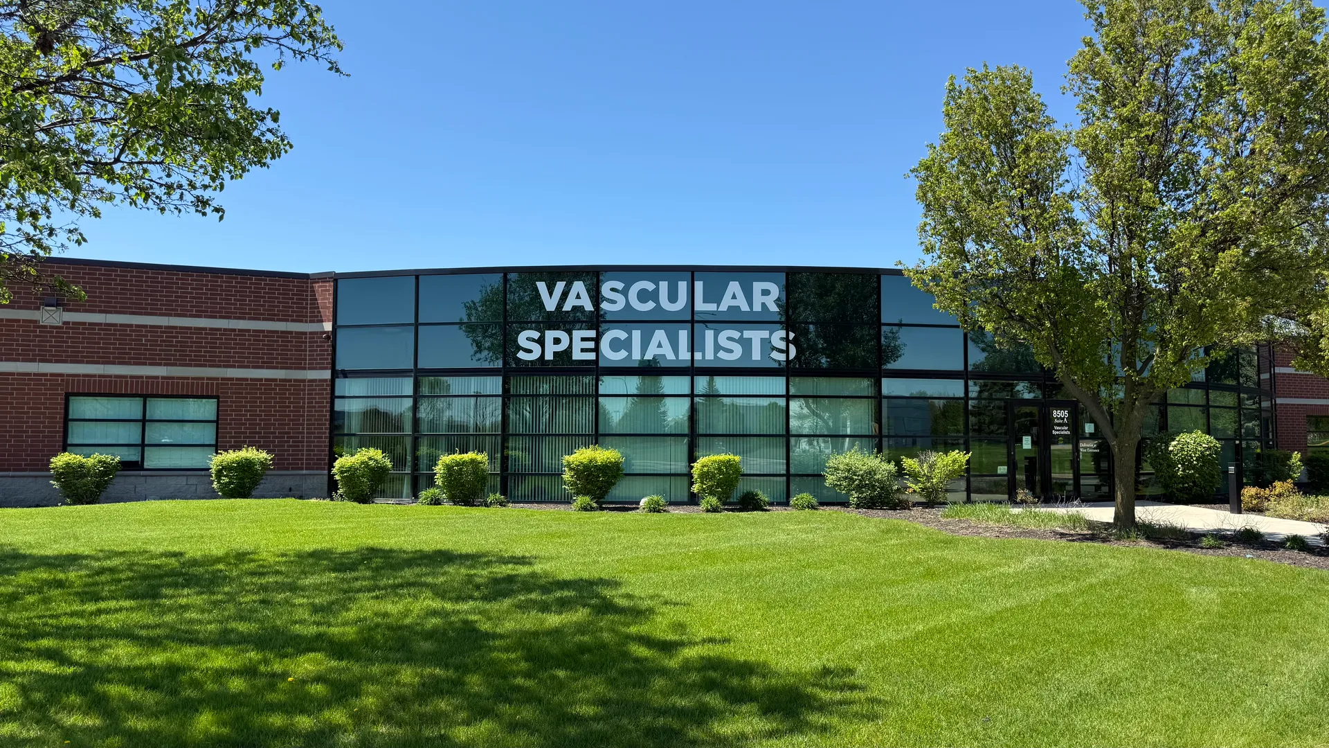 Exterior of the Tinley Park office at 8505 183rd St., Suite A — a brick and glass building with a Vascular Specialists sign, set behind a green lawn and trees